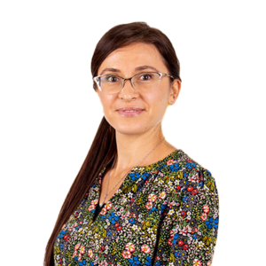 Inga Grosu, Chesterton House Accountant. Headshot of Inga, who is looking at the camera with an open expression and a smile. She has long dark hair draped over her right shoulder. She is wearing classes and a floral dress.